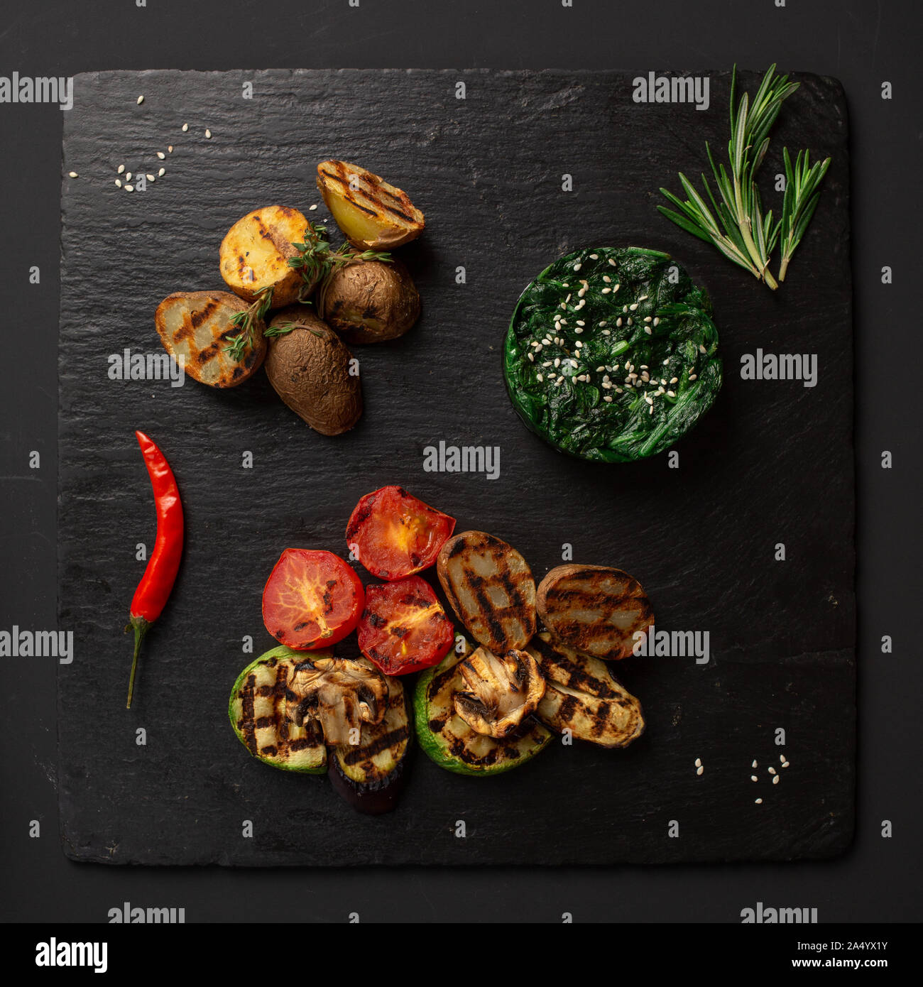 Chuka und Salat gebackenes Gemüse auf einem schwarzen Brett mit Pfeffer und Kräutern dekoriert Stockfoto
