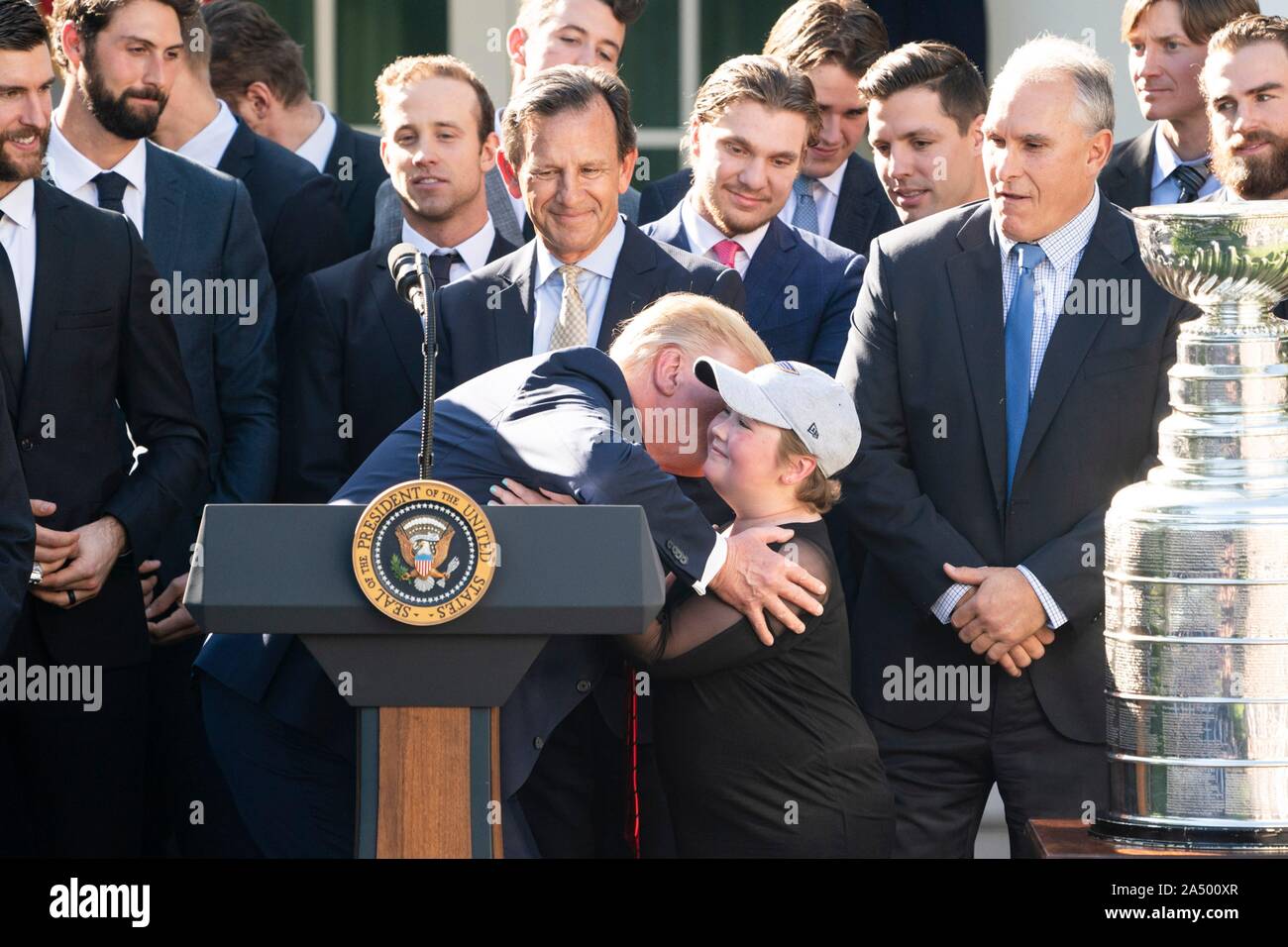 Us-Präsident Donald Trump, Zentrum, umfasst der St. Louis Blues super Fan Laila Anderson, während einer Zeremonie, begrüßte die 2019 Stanley Cup professional Ice Hockey Team, die St. Louis Blues, im Rosengarten des Weißen Hauses Oktober 15, 2019 in Washington, DC. Stockfoto