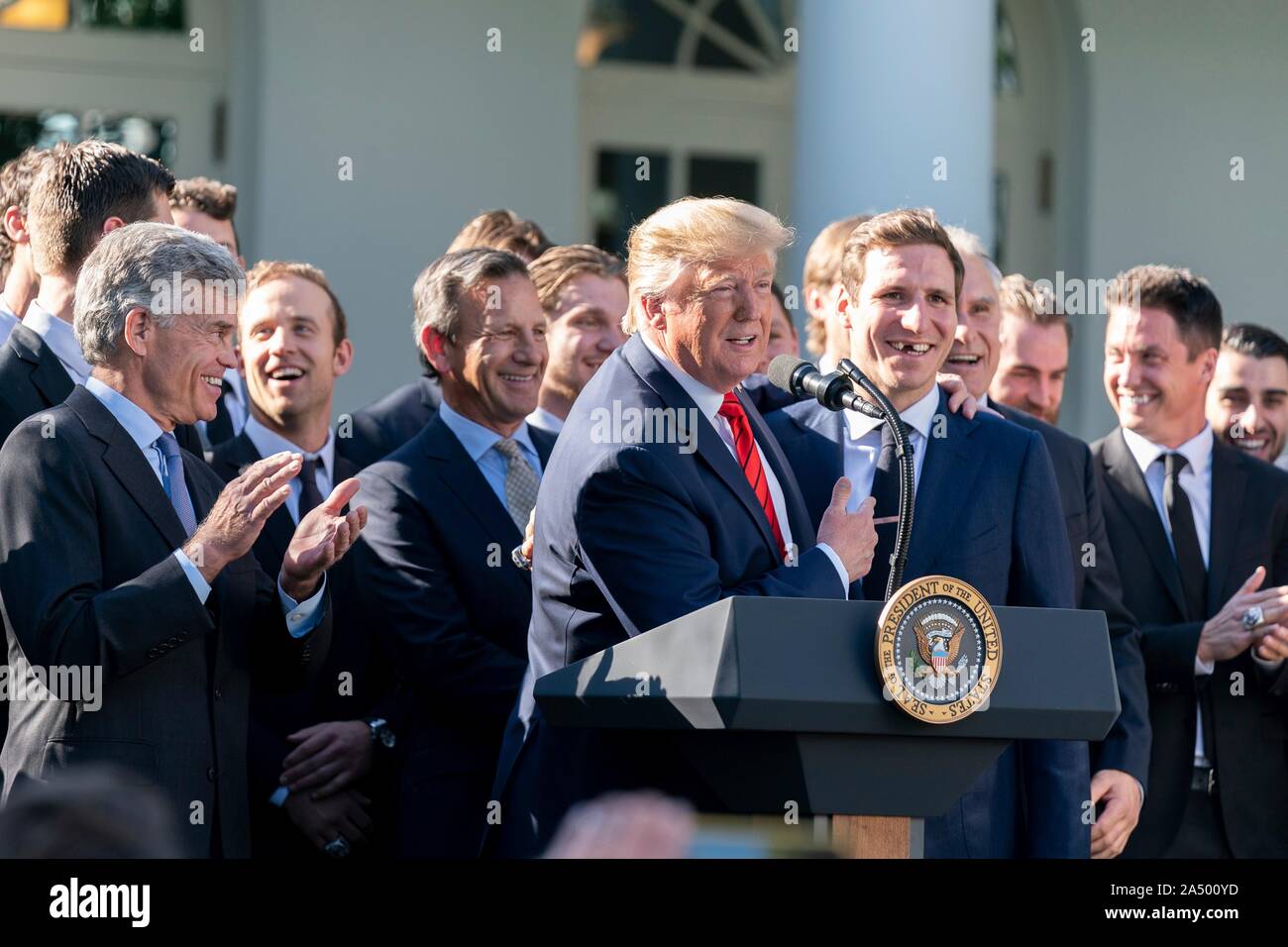 Us-Präsident Donald Trump, Zentrum, umfasst der St. Louis Blues player Alex Steen, als Teambesitzer Tom Stillman, Links, auf die im Rahmen einer Feierstunde begrüßte die 2019 Stanley Cup professional Ice Hockey Team freut, die St. Louis Blues, im Rosengarten des Weißen Hauses Oktober 15, 2019 in Washington, DC. Stockfoto