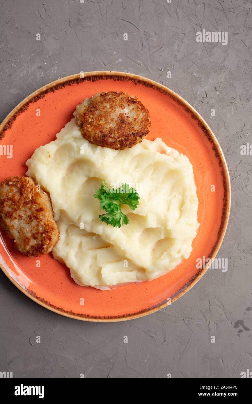 Gestampfte Kartoffeln und Fleisch Schnitzel in einem orange Platte auf grauem Hintergrund Stockfoto