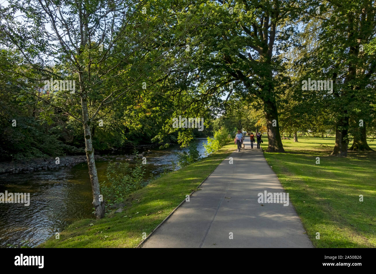 Menschen, die entlang des Fußwegs am Fluss Greta in Fitz Park Keswick Lake District National Park Cumbria England Großbritannien Großbritannien Stockfoto