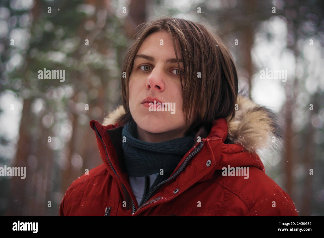 Ein hübscher Kerl in der roten Jacke ist zuversichtlich, dass sich in der Mitte der Kiefer Winter Forest und sieht aus kalten Herzlosen ein hartes Leben. Stockfoto