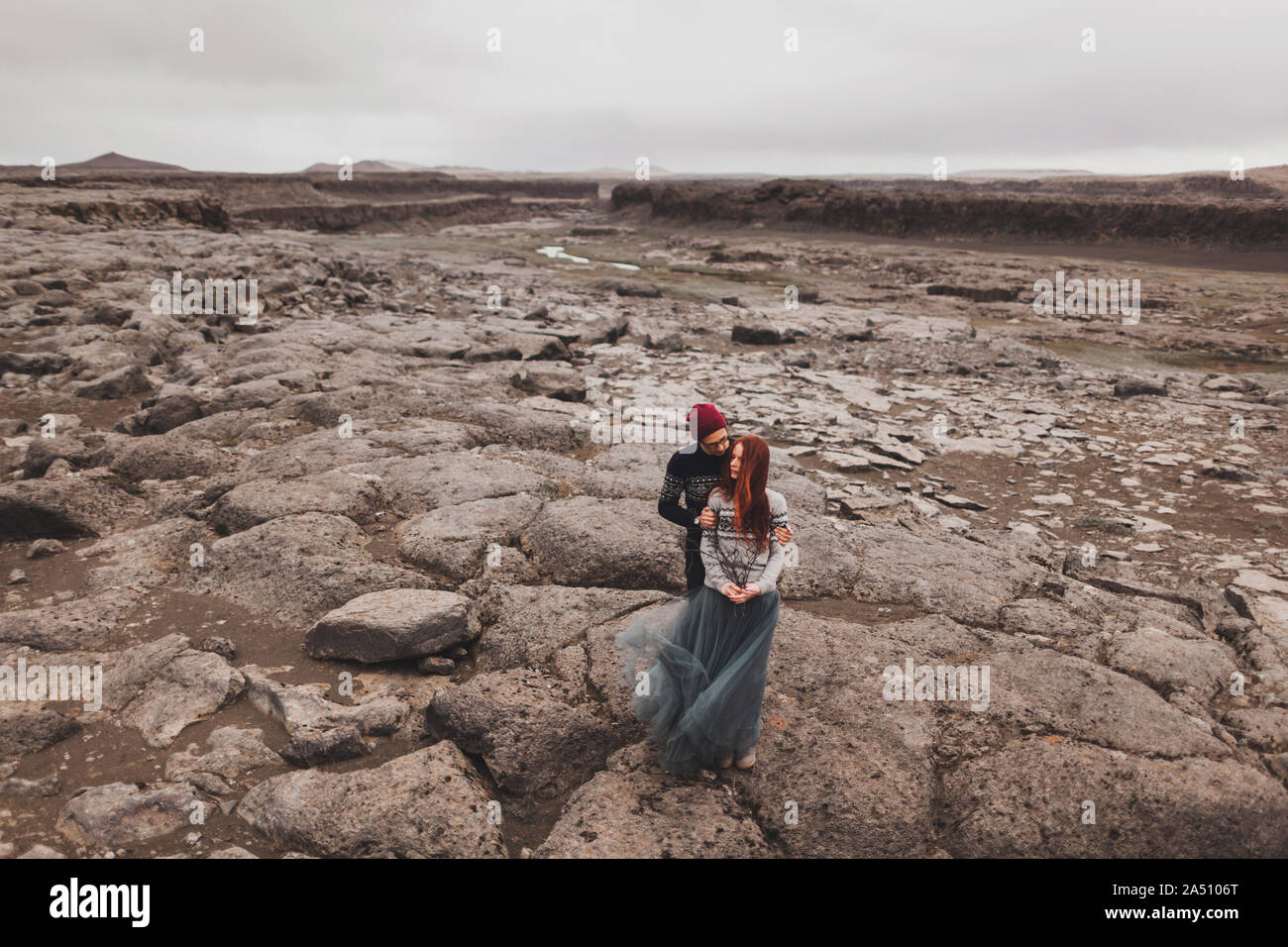 Paare, die in Liebe zu küssen und in Island. Stein vulkanischen Wüste herum, in der Mitte von Nirgendwo. Dramatische nordischen Landschaft, bei kaltem Wetter. Das Tragen der traditionellen wolle Pullover, Jeans und Rock. Stockfoto