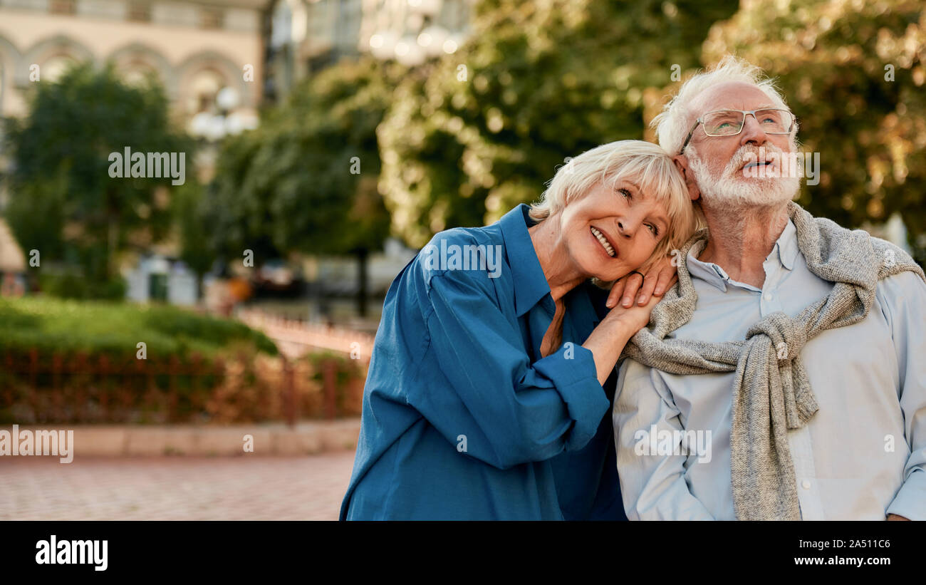 So glücklich zusammen. Portrait von Schöne ältere Frau lehnte sich an die Schulter ihres Mannes und lächelnd, während man im Freien an einem sonnigen Tag Stockfoto