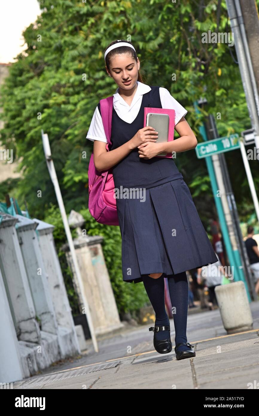 Female College Student trägt Uniform zu Fuß auf dem Bürgersteig Stockfoto
