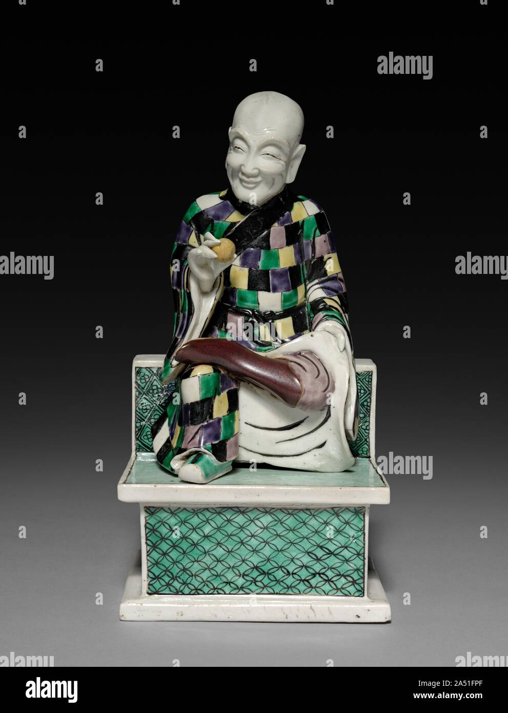 Lohan Holding einen Pfirsich, 1662-1722. Diese Lohan, Schüler von Buddha mit übernatürlichen Kräften, war vielleicht Teil eines Hauses Altar oder ein dekoratives Element in einem Haushalt. Lohans, auch als arhats bekannt sind, sind so zu zähmen Tiger in der Lage zu sein und treten auf dem Wasser. Diese Lohan mit einem kahlen Kopf ist als monklike Abbildung gezeigt, trägt einen Mönch ’s Robe aus Patches und Halten der Pfirsich der Unsterblichkeit. Diese Lohan und seine Paar, ein fu-Hund (1964.191.2) verkörpern eine humorvolle Haltung und spielerische Verhalten, Gleichgültigkeit zu Gefahr und Wunder, und daher eine Loslösung von den weltlichen Angelegenheiten. Während der 1600s Stockfoto