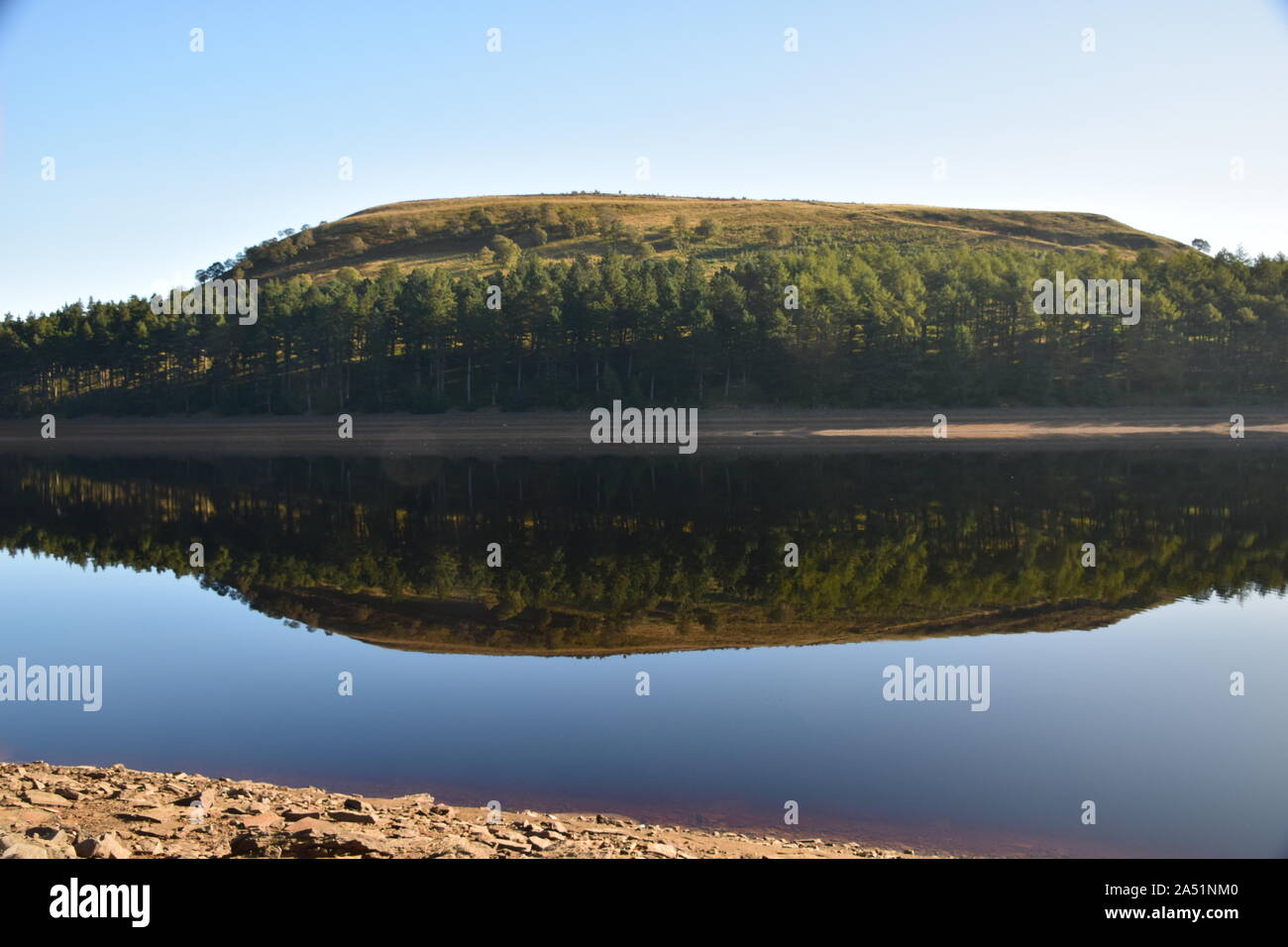 Howden Reservoir derbyshire england, das den Himmel und die Ufer zeigte, die sich Mitte Sommer auf der Stillwasseroberfläche niederschlugen Stockfoto