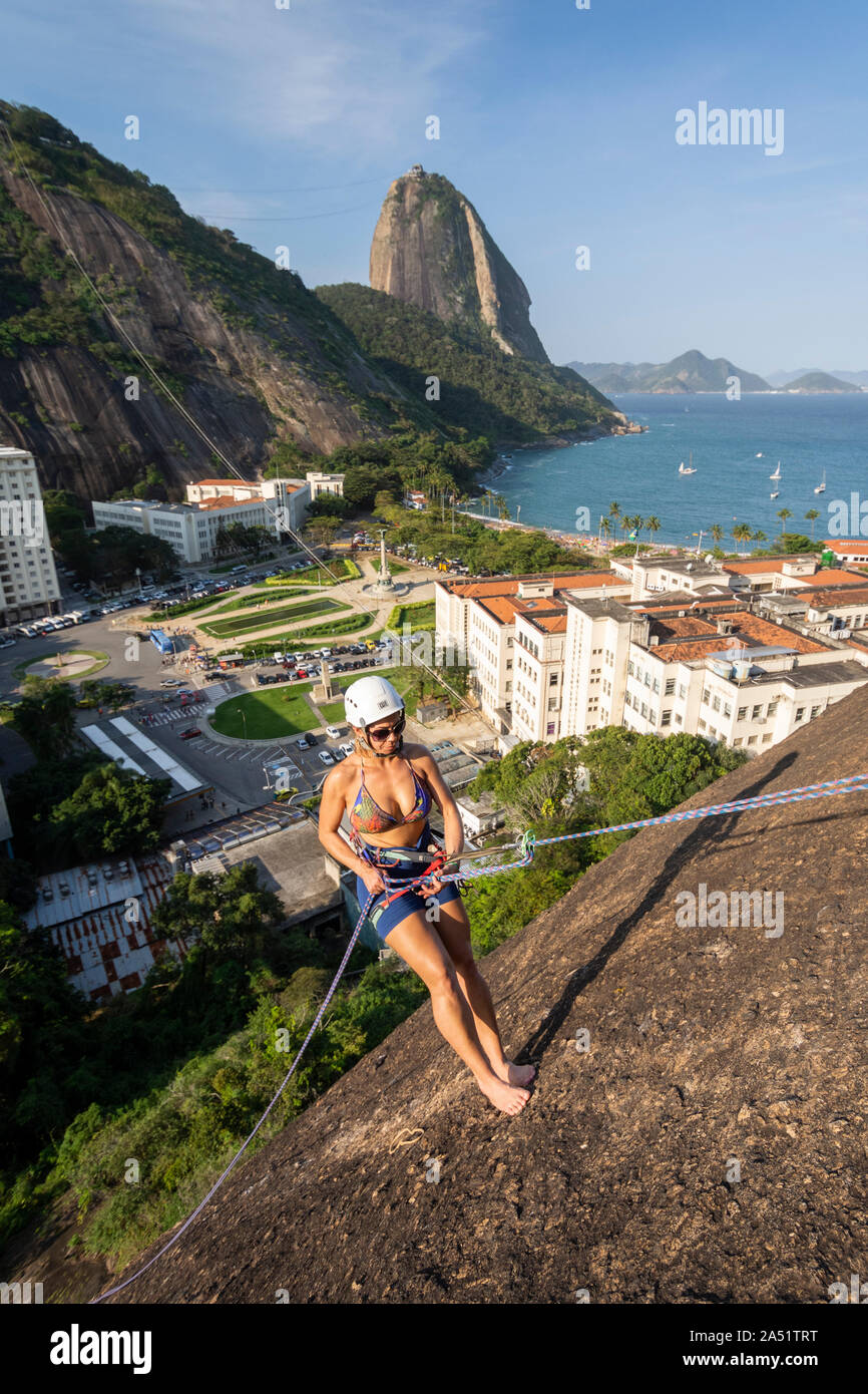 Frau Klettern auf der wunderschönen Landschaft mit Zuckerhut auf der Rückseite, Urca, Rio de Janeiro, Brasilien Stockfoto