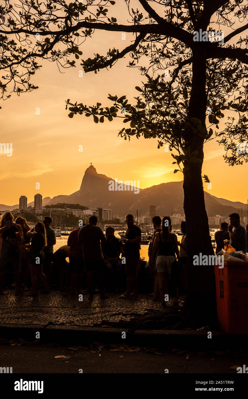 Schöne Aussicht auf den Sonnenuntergang von Freunden sozialisieren und Trinken durch die Ocean Walk in Mureta da urca mit Berg Corcovado auf der Rückseite, Rio de Janeiro, Bra Stockfoto