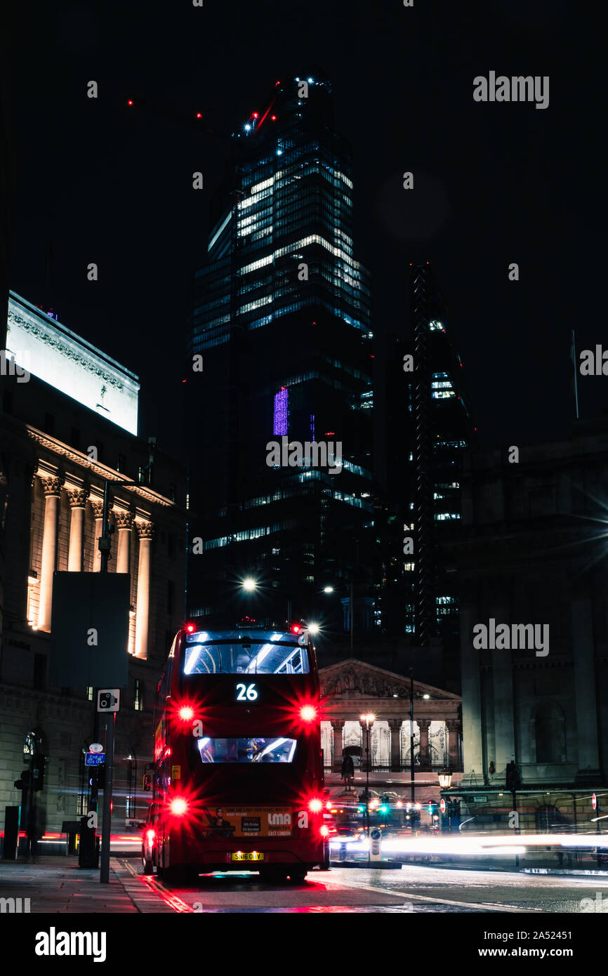 Blick auf die Straße von Geschäftshäusern und öffentlichen Verkehrsmitteln in London red Bus bei Nacht 1/2 Stockfoto