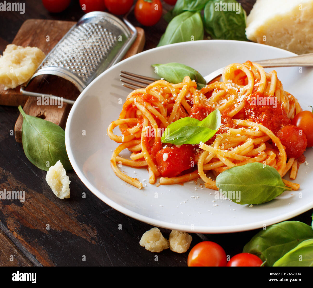 Spaghetti Pasta mit Tomatensauce, Basilikum und Käse auf einem Holztisch Stockfoto