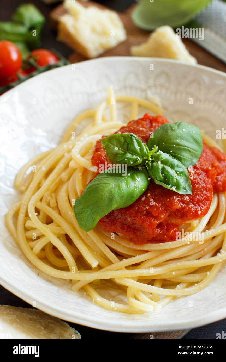 Spaghetti Pasta mit Tomatensauce, Basilikum und Käse auf einem Holztisch Stockfoto