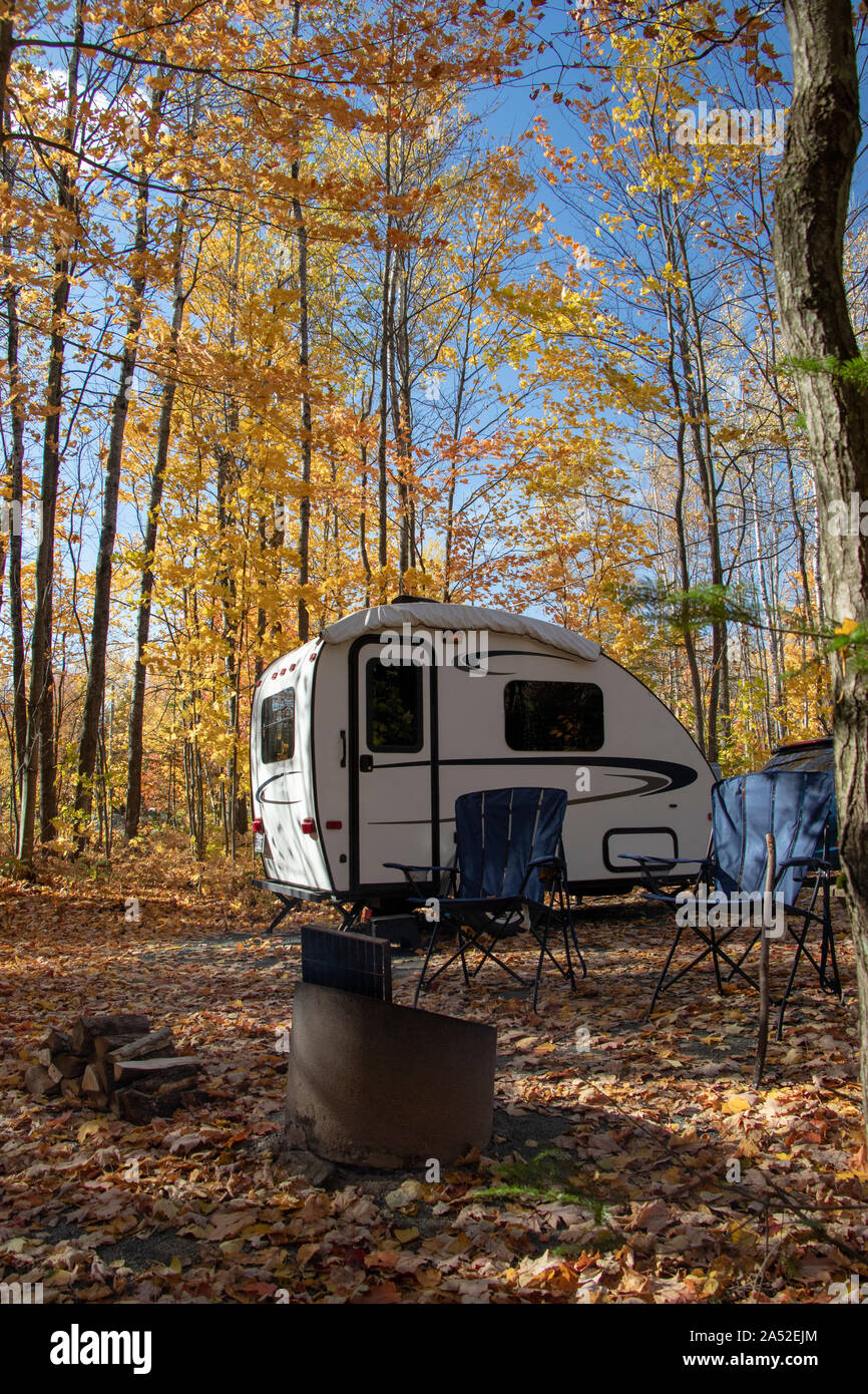 Ein kleines Teardrop-Anhänger-Fahrzeug und zwei Campingstühle in der Herbstsaison (kein Logo, Logo entfernt), RVing, Wohnmobil-Stellplätze; Caravaning Stockfoto