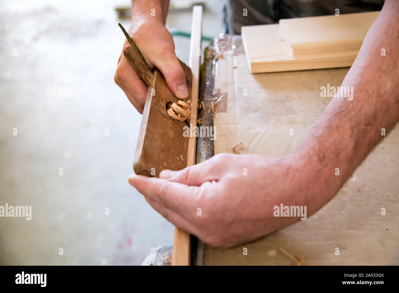 Tischler mit einem Planer auf ein Brett aus Holz in einem Holzbearbeitung Workshop in einer Nahaufnahme auf seine Hände, die Holzteile auf der Werkbank Stockfoto
