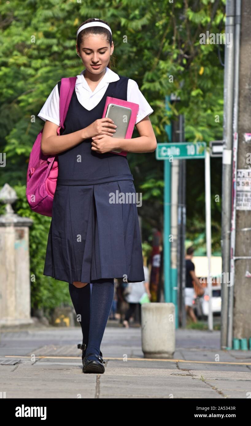 Female College Student trägt Uniform zu Fuß auf dem Bürgersteig Stockfoto