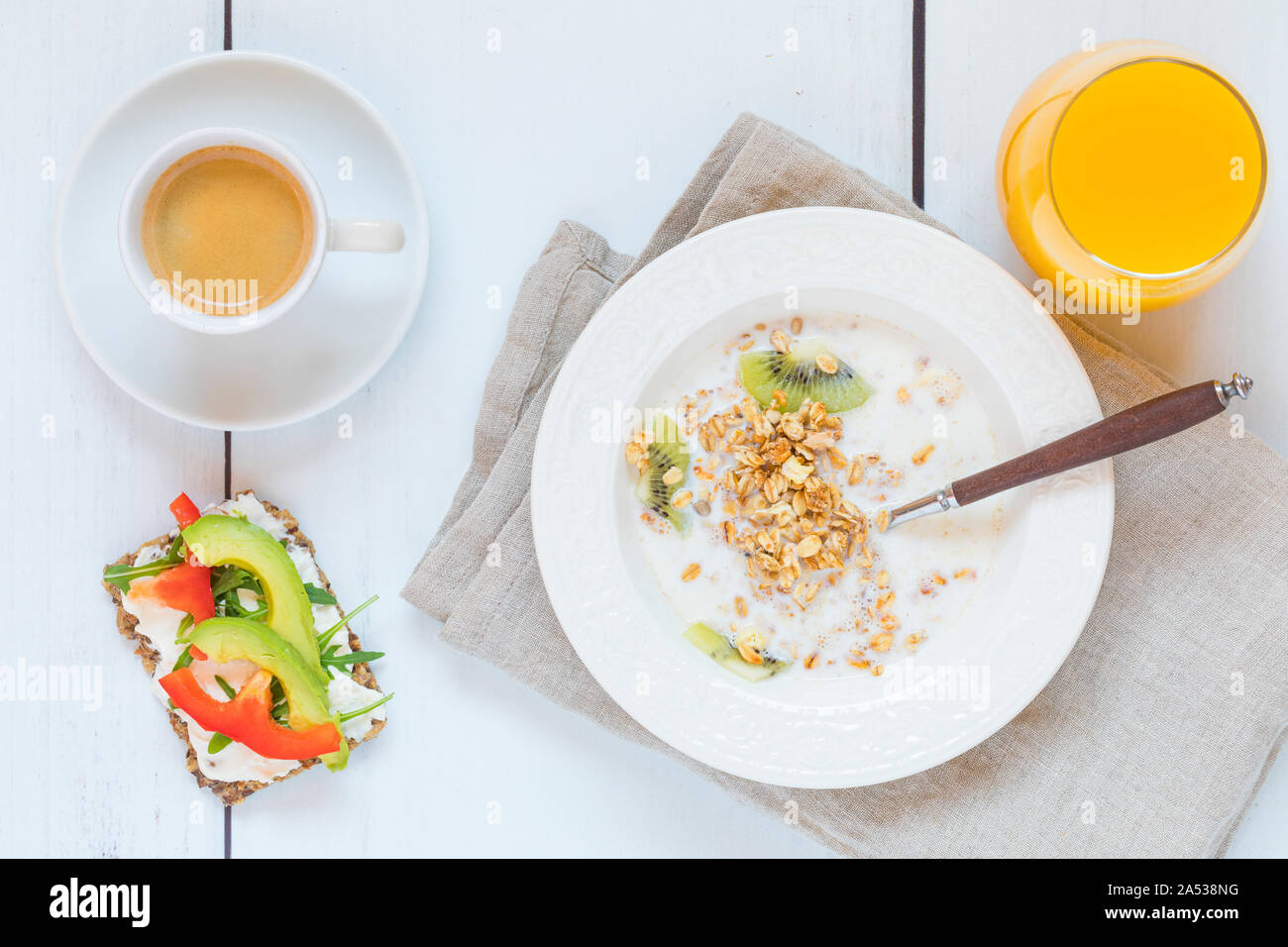 Ein gesundes Frühstück mit hausgemachten Bio Müsli, Orangensaft, Brot mit Avocado, Rucola und Paprika. Direkt von oben gesehen flach legen pro Stockfoto