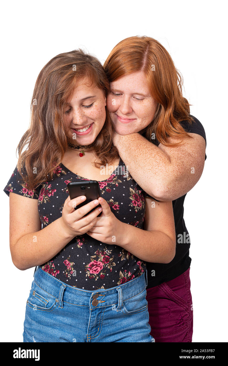 Vertikale studio Schoß einer Mutter, die sich an die Schulter ihres Tochter ihr nutzen ihr Handy zu beobachten. Sie sind beide lächelnd. Weißer Hintergrund. Stockfoto