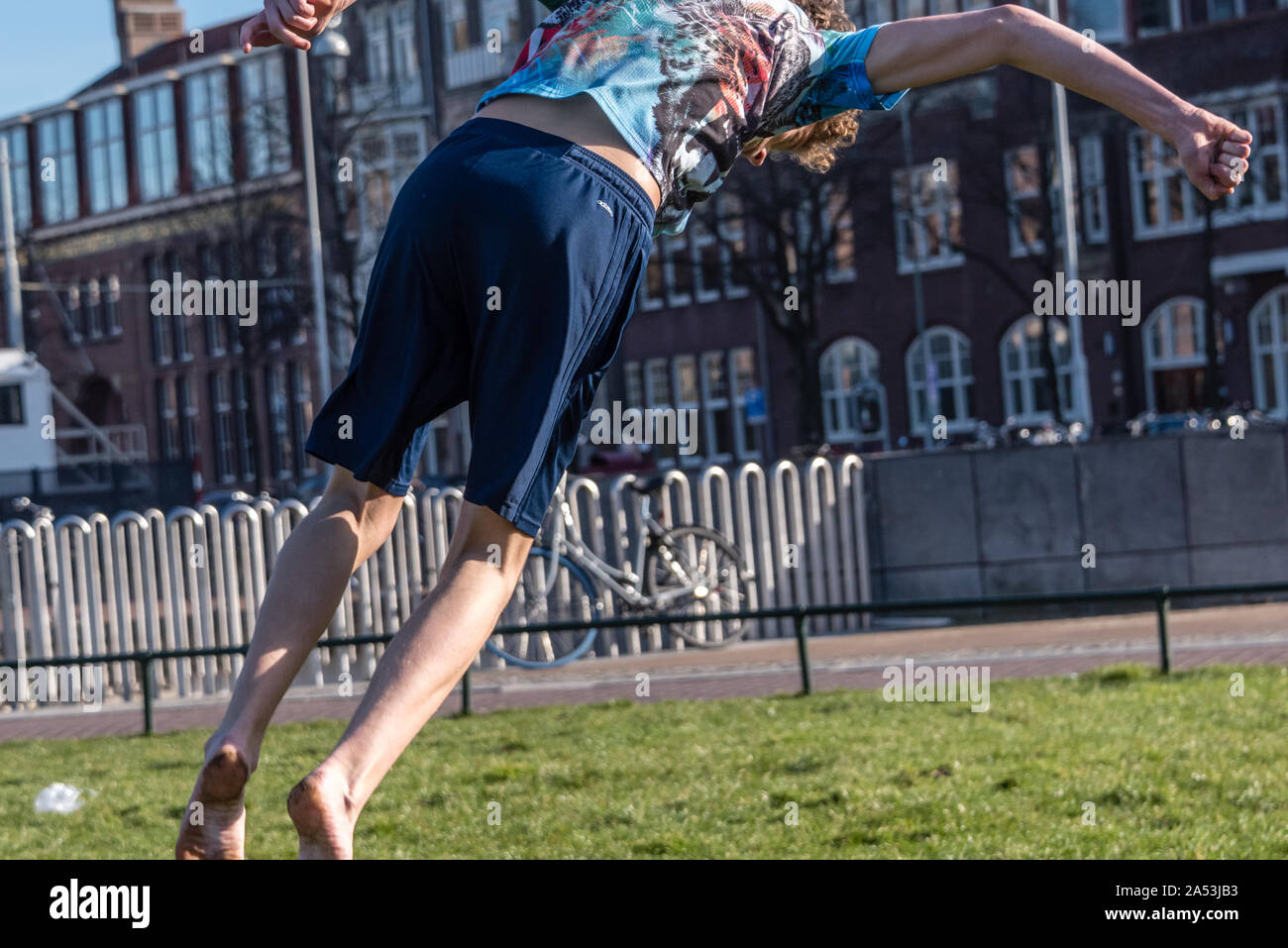 Amsterdam, Holland, 25. Februar 2019 Straße spiegeln Junge auf dem Gras der Museumplein in Amsterdam in seine Shorts an einem sonnigen Tag Stockfoto