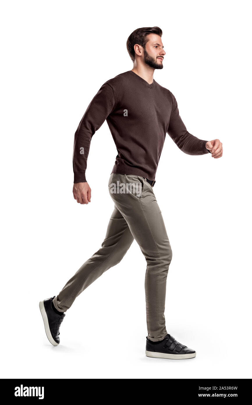 Ein junger bärtiger Mann in Seitenansicht geht schnell auf der Kante des läuft auf einem weißen Hintergrund. Stockfoto