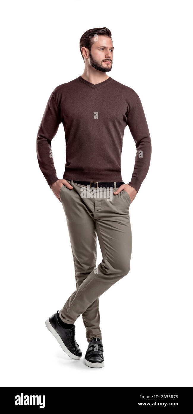 Ein Mann in den Hosen, Pullover und Turnschuhe steht mit einem Bein über einen anderen und suchen seitwärts. Stockfoto