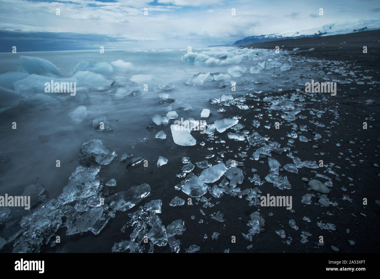 Eisberge in der Brandung brechen ein remote Black Sand Beach im Süden Islands verlassen, mit der Darstellung von mit Glasscherben übersät. Stockfoto