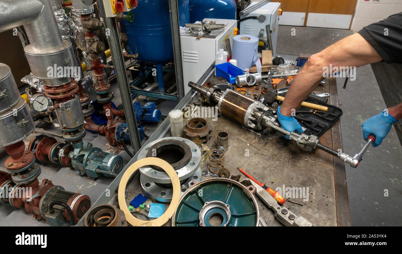 Maschinenbauer in Latex Handschuhe Lager aus der einen Anker auf seiner Werkbank in einem Pumpenraum Stockfoto