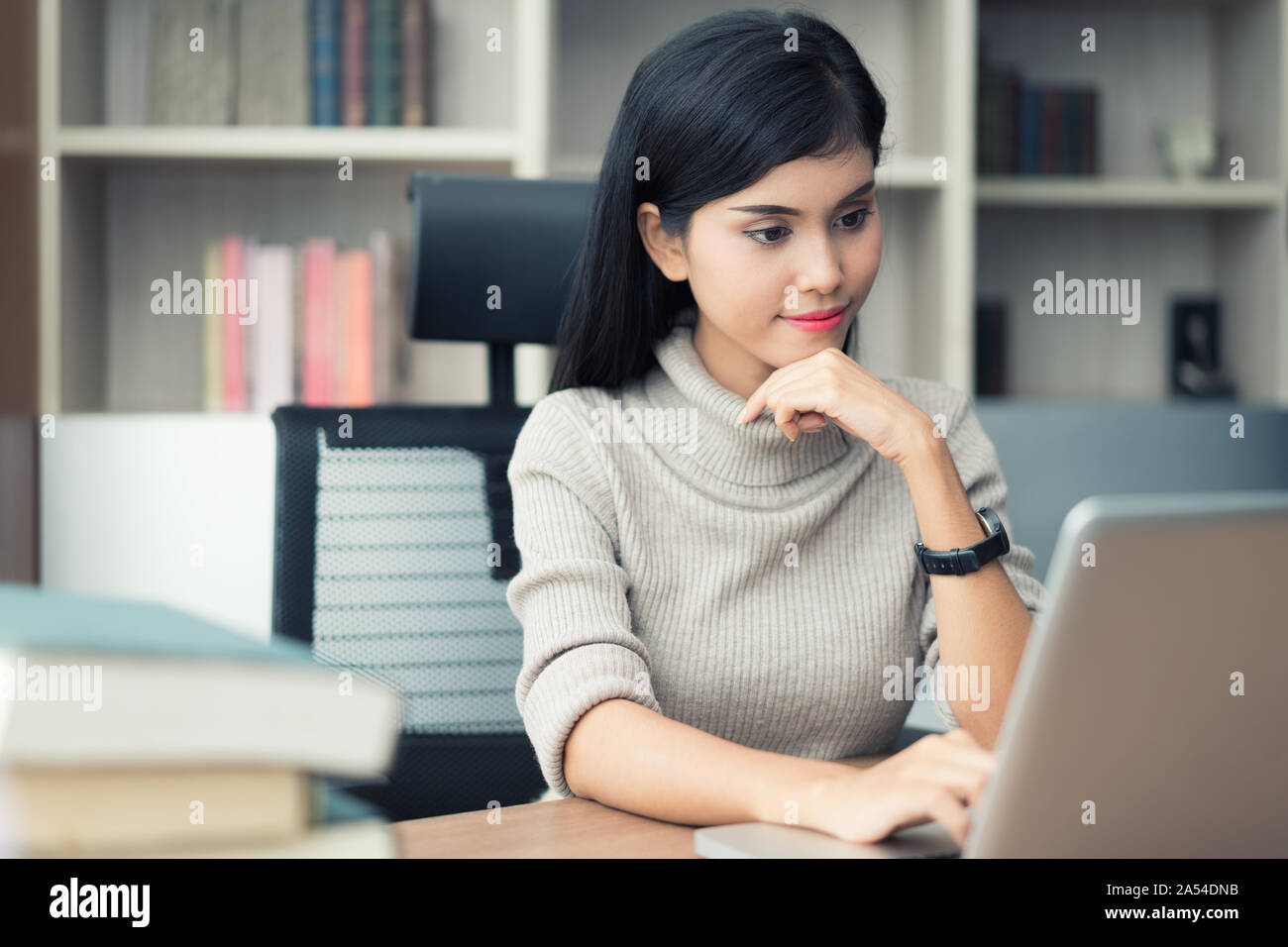 Asiatische junge intelligente Frau Manager mit casual Ihr Geschäft arbeiten mit Laptop und sitzen auf Stuhl Gefühl im legeren Outfit überzeugt. Headshot von f Stockfoto