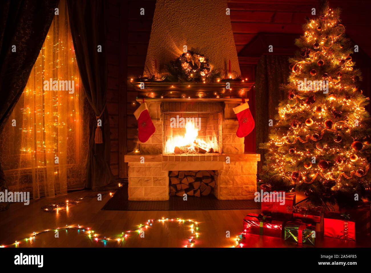 Weihnachten eingerichtetes Wohnzimmer mit Kamin, Sessel, Fenster und Xmas Tree Stockfoto