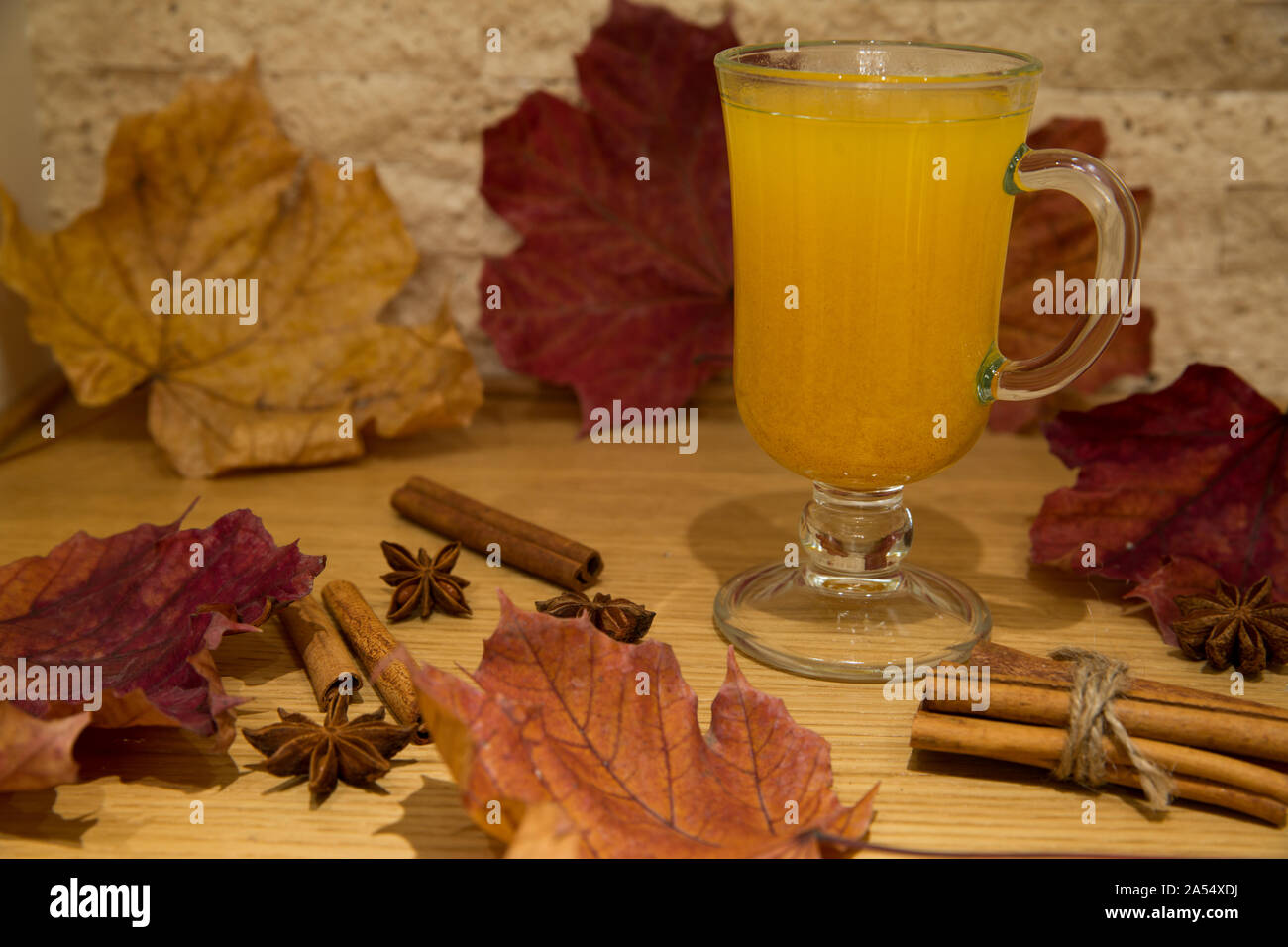 Tee aus Sanddorn Beeren und Gewürzen. Herbst Szene mit Anis Sterne und Zimtstangen, Dekoration von getrockneten bunten Blättern: rot, orange und gelb Stockfoto