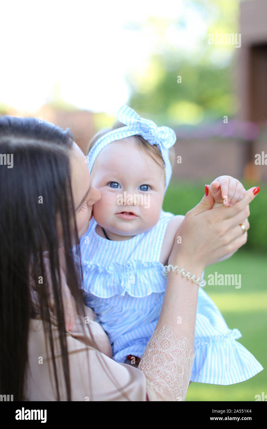 Closeup glücklich aucasian Mutter halten wenig weibliches Kind in blauem Kleid. Stockfoto