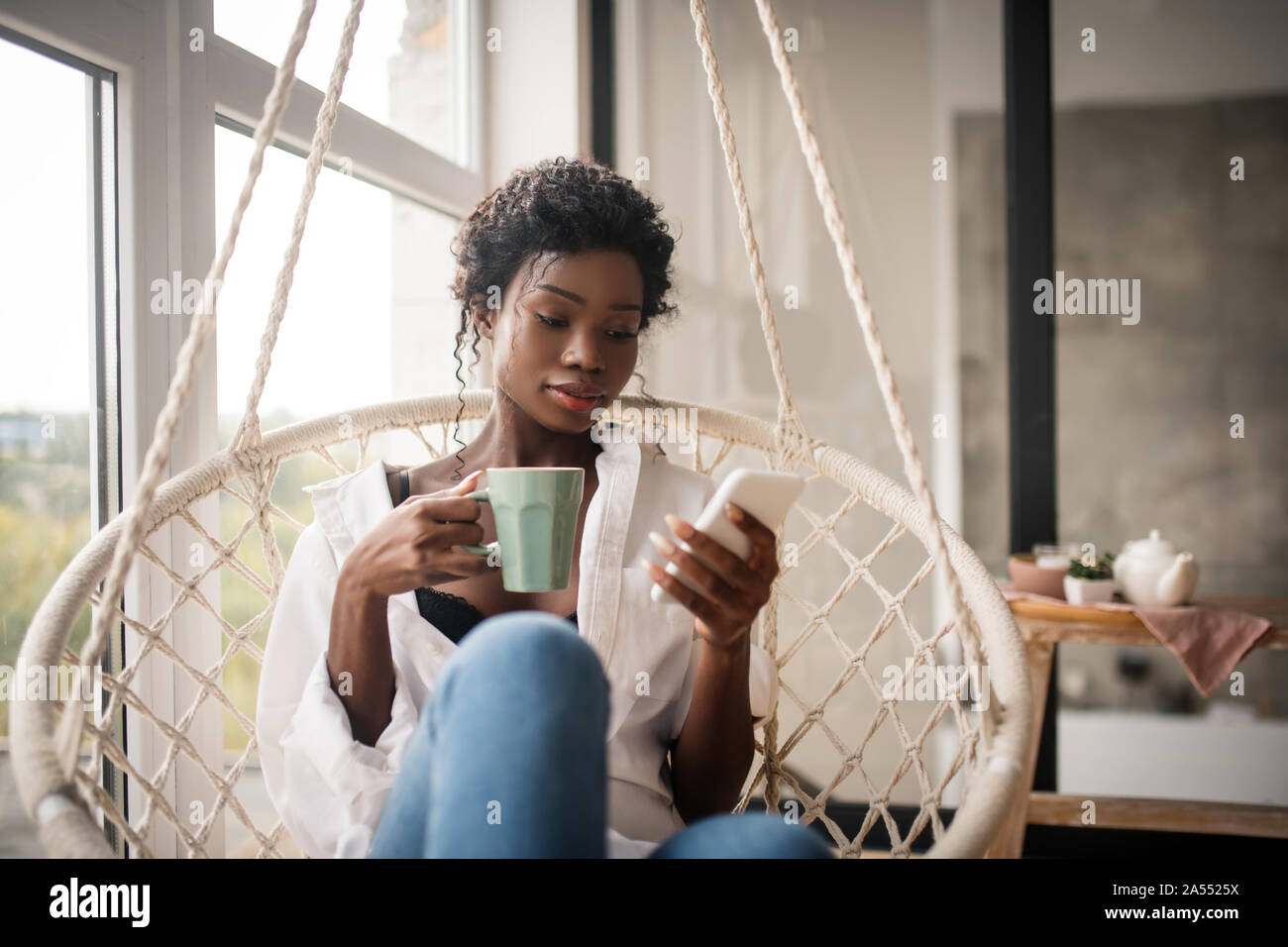 Curly Frau sitzen und Kaffee trinken, während das Lesen von E-Mails Stockfoto