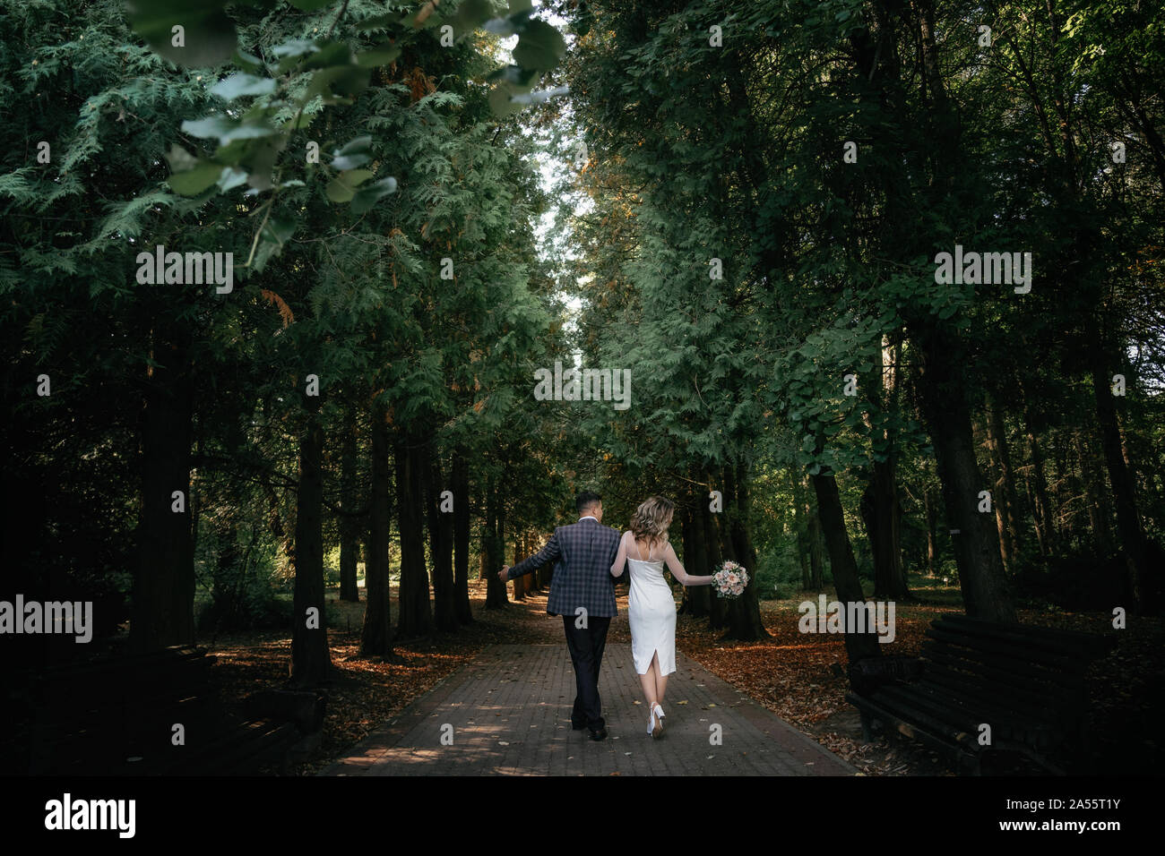 Hochzeit paar Spaziergänge entlang einem dunklen Wald Weg Stockfoto