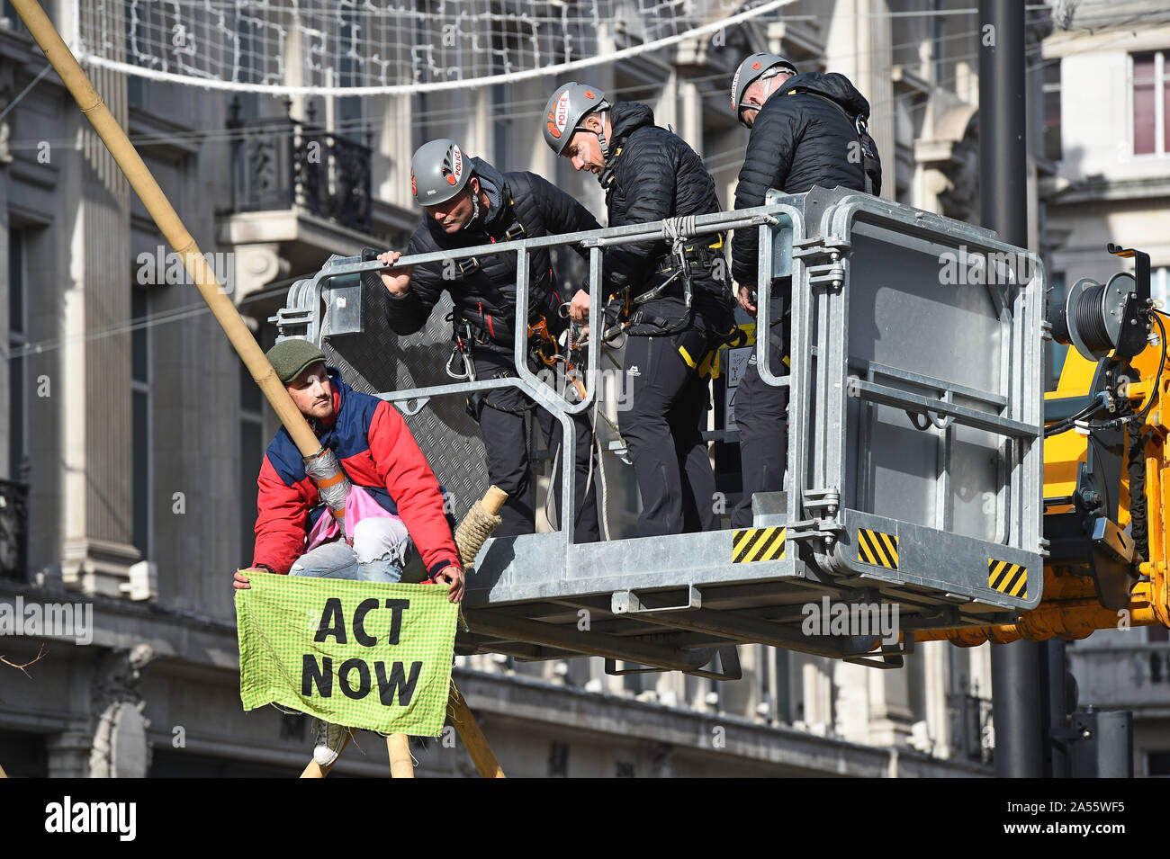 Polizei versucht eine Demonstrantin, die saß auf einem Bambus Struktur der Straße am Oxford Circus, London, während einer Aussterben Rebellion (XR) Klimawandel protest Block ist zu entfernen. Stockfoto