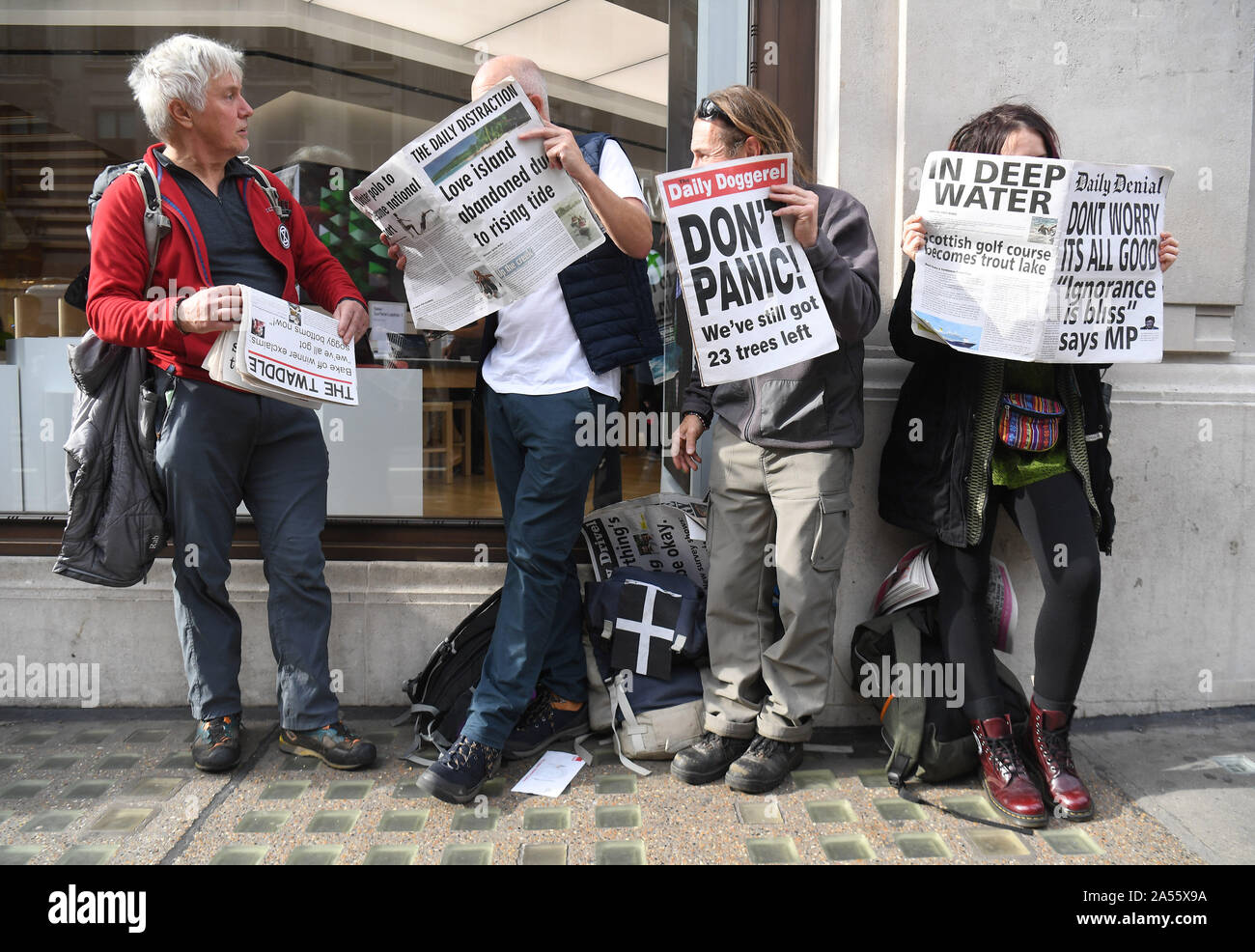 Die Demonstranten lesen Mock-up-Zeitungen in Oxford Circus, London, während ein Aussterben Rebellion (XR) Klimawandel protestieren. Stockfoto
