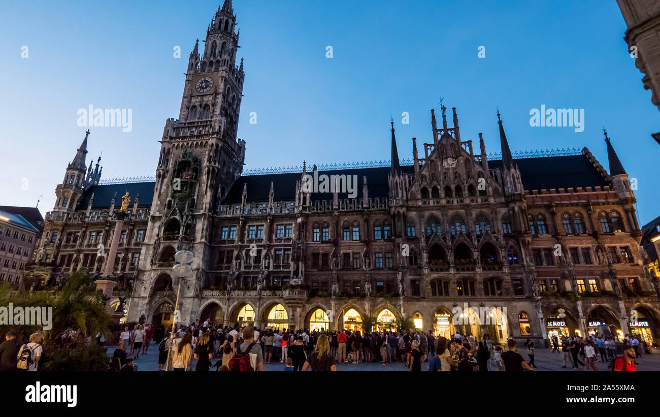 München 2019. Touristen bewundern und fotografieren die Neues Rathaus bei Sonnenuntergang an einem Sommertag. August 2019 in München. Stockfoto
