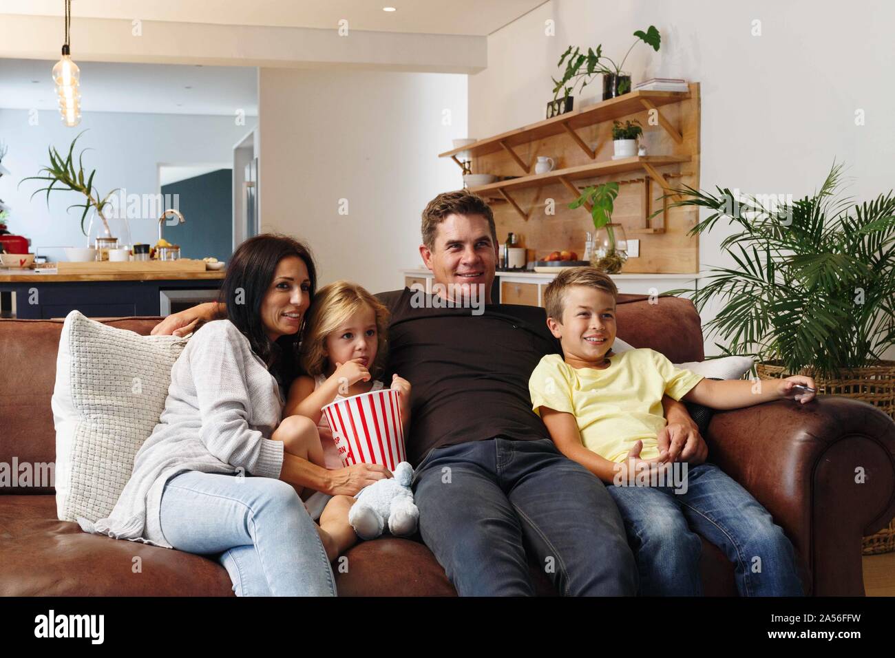 Eltern und Kinder entspannen mit Popcorn auf dem Sofa zu Hause Stockfoto