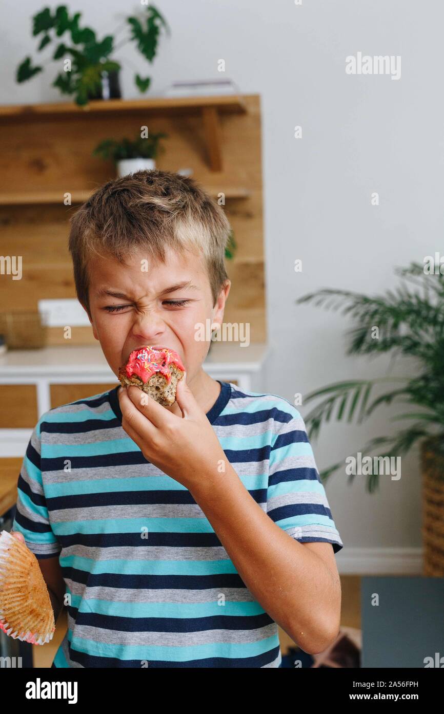 Junge beißen in Cupcake zu Hause Stockfoto