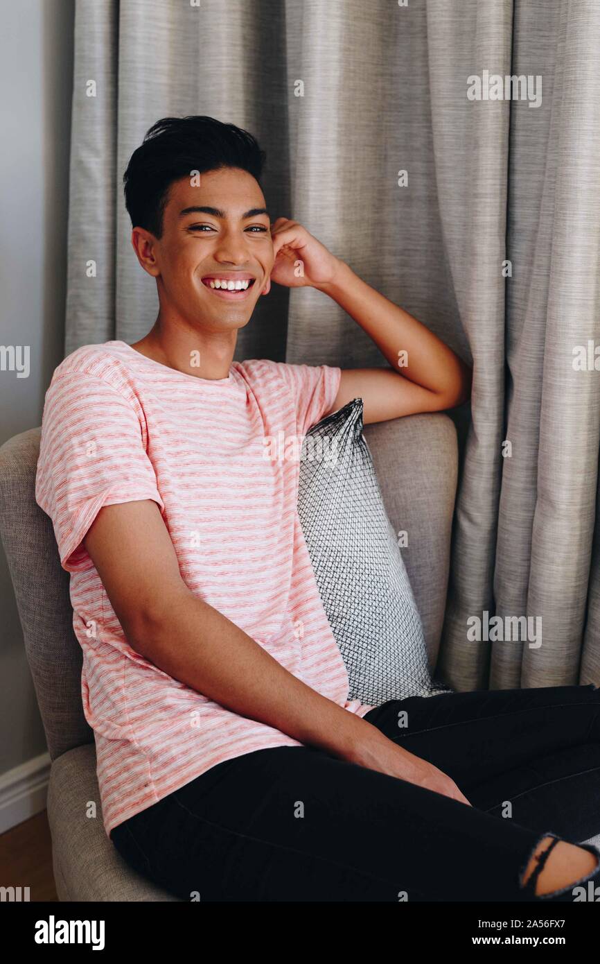 Glückliche junge Mann sitzt auf Schlafzimmer Stuhl, Porträt Stockfoto