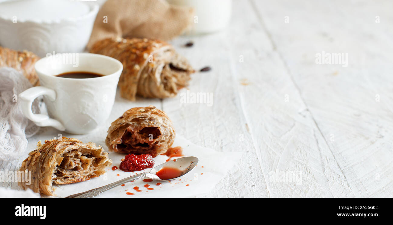Frühstück mit Kaffee und Croissants mit Erdbeermarmelade Nahaufnahme Stockfoto