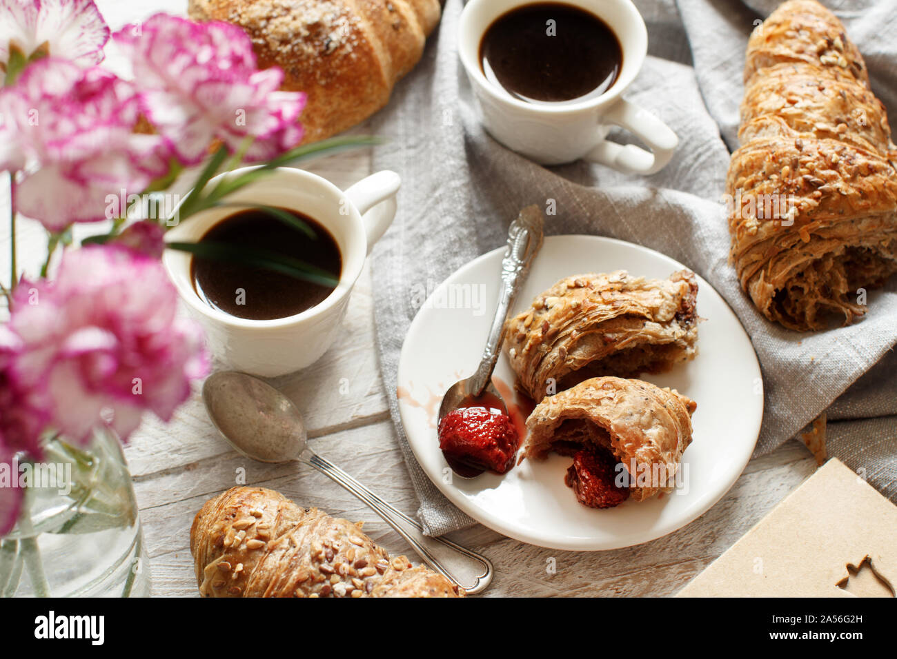 Frühstück mit Kaffee und Croissants mit Erdbeermarmelade Nahaufnahme Stockfoto