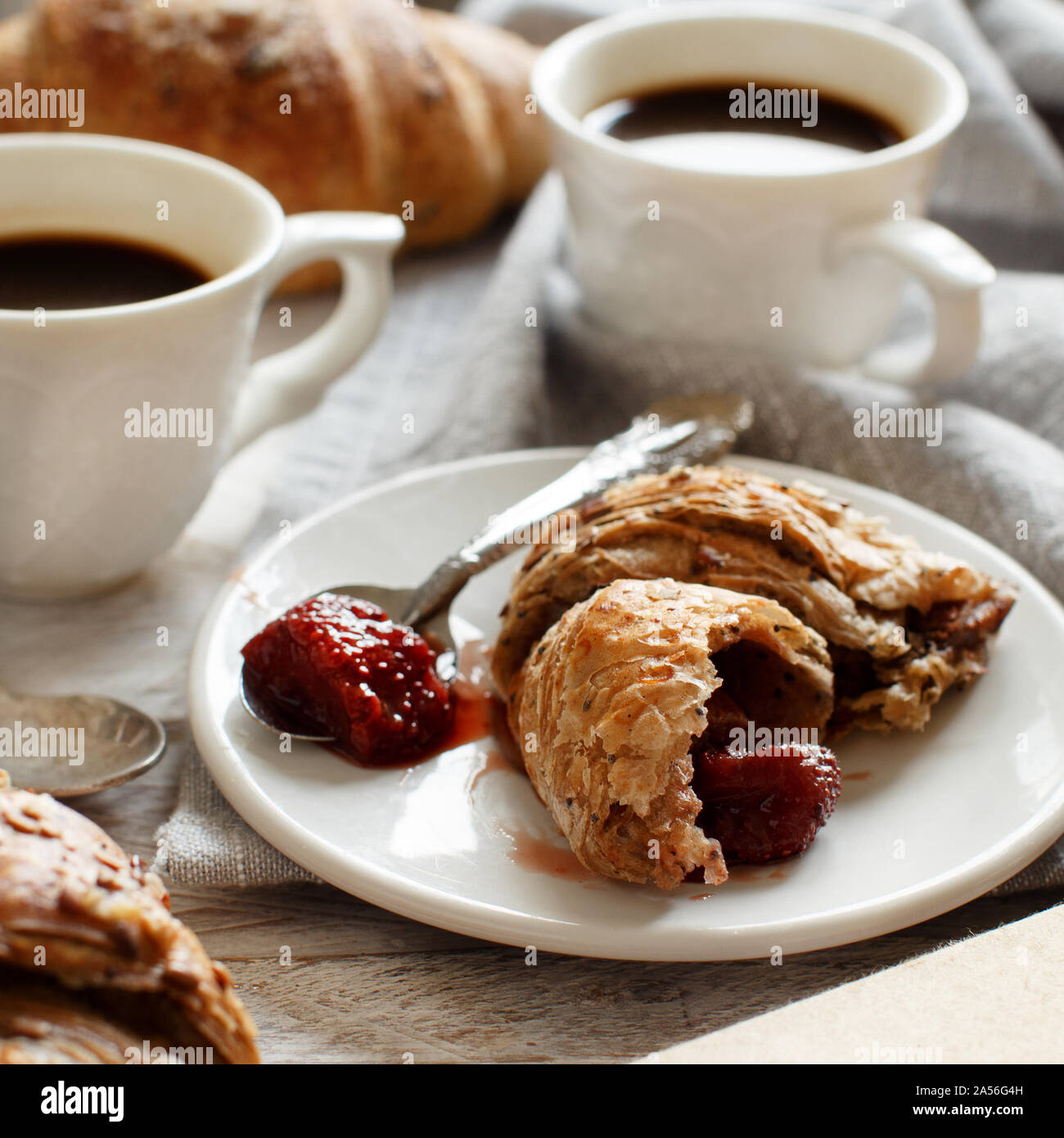 Frühstück mit Kaffee und Croissants mit Erdbeermarmelade Nahaufnahme Stockfoto
