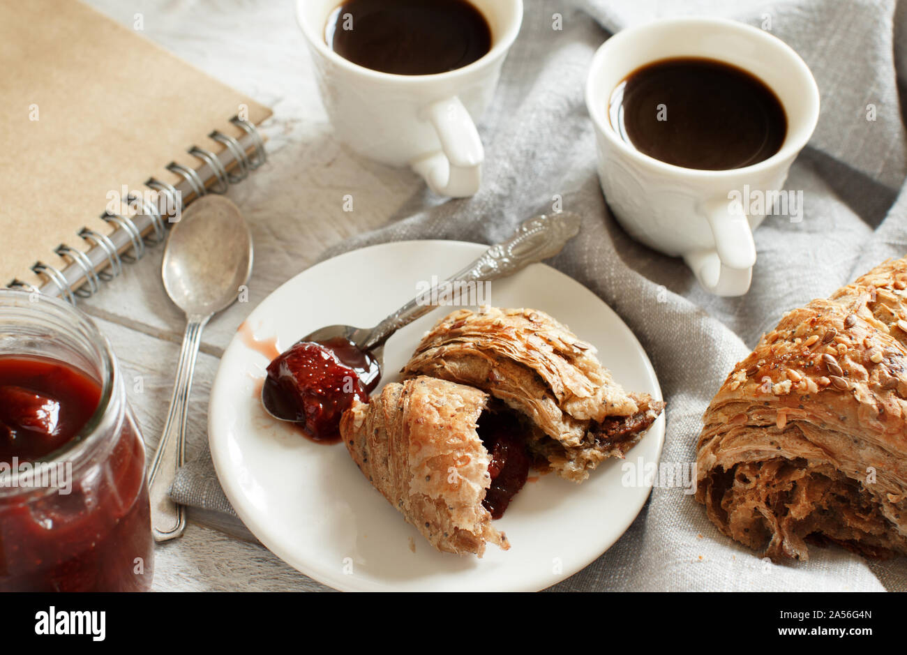 Frühstück mit Kaffee und Croissants mit Erdbeermarmelade Nahaufnahme Stockfoto