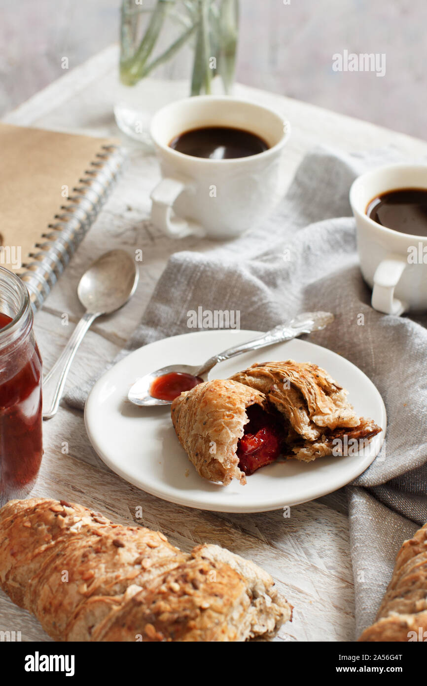 Frühstück mit Kaffee und Croissants mit Erdbeermarmelade Nahaufnahme Stockfoto