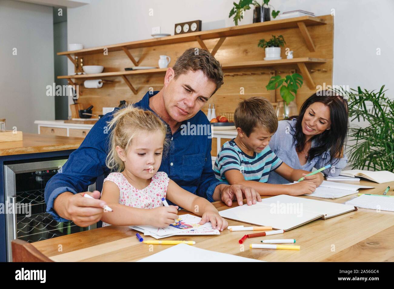 Eltern helfen den Kindern bei den Hausaufgaben zu Hause Stockfoto