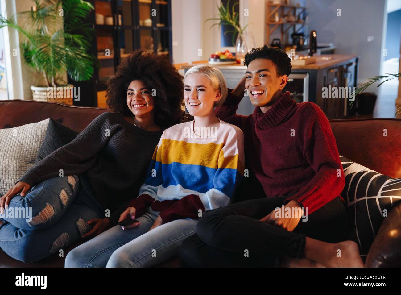 Gerne Mitte erwachsenen Mann und Junge weibliche Freunde Fernsehen auf Sofa im Wohnzimmer Stockfoto