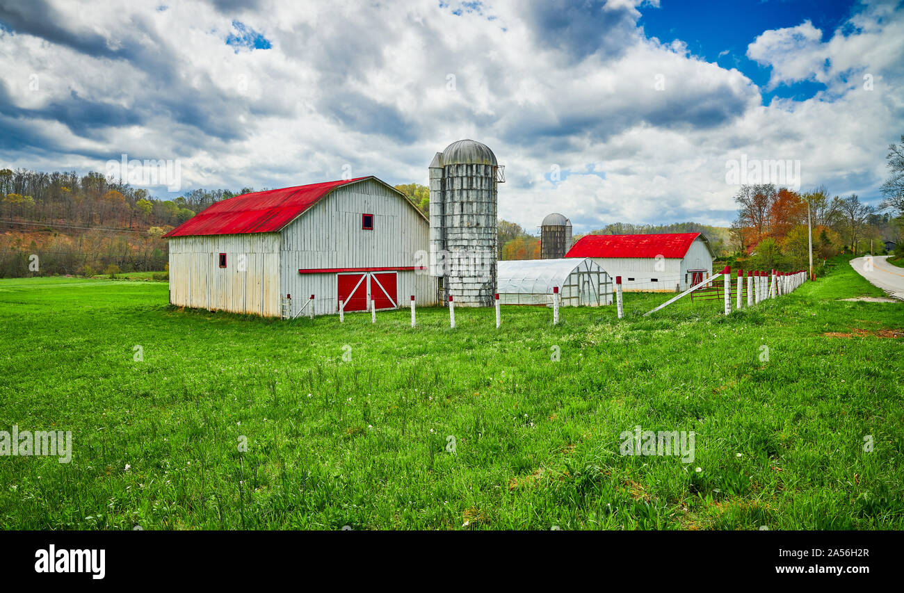 Red Roof Scheune und Silo entlang einer Landstraße. Stockfoto