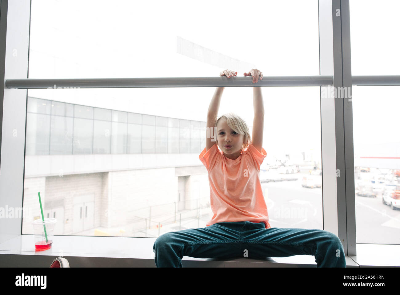 Junge holding Handlauf in Flughafen Fensterplatz, drei viertel länge Porträt Stockfoto