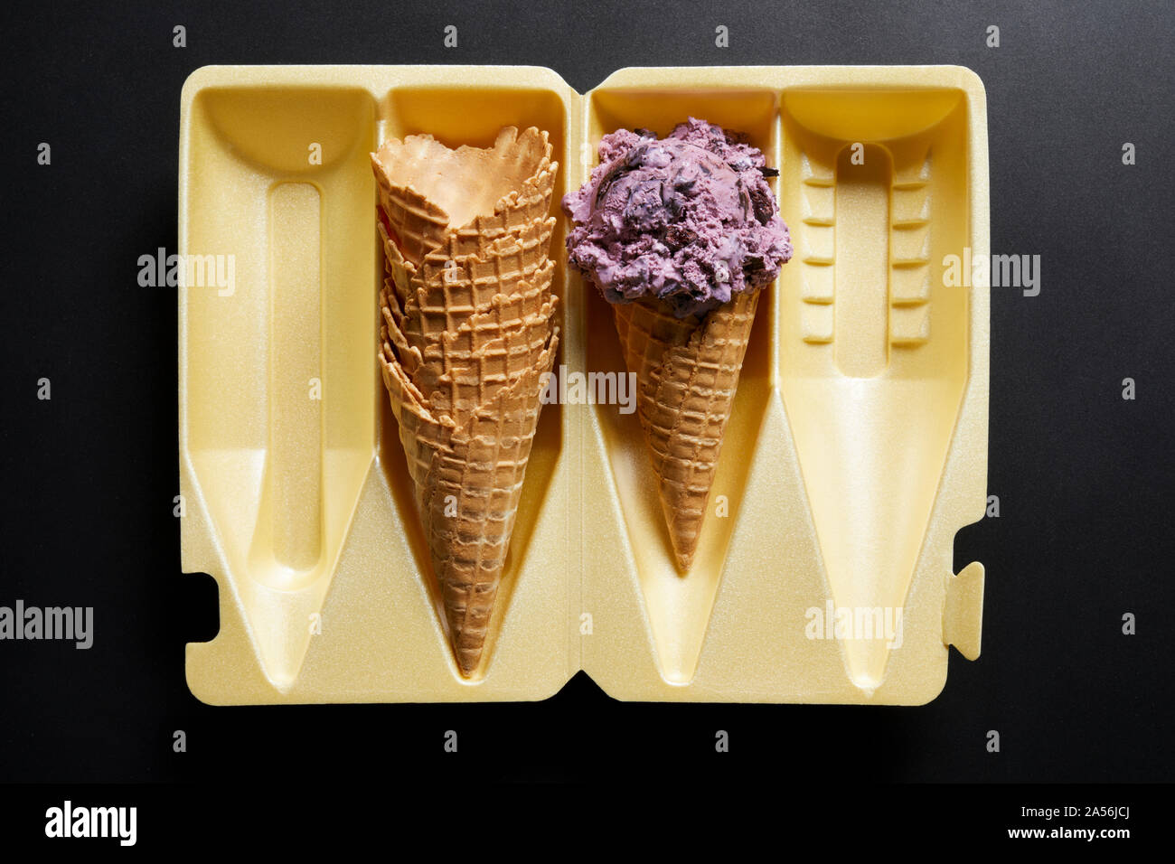 Eis Kegel und Stapel von Waffeln in der Verpackung auf schwarzem Hintergrund, Ansicht von oben Stockfoto