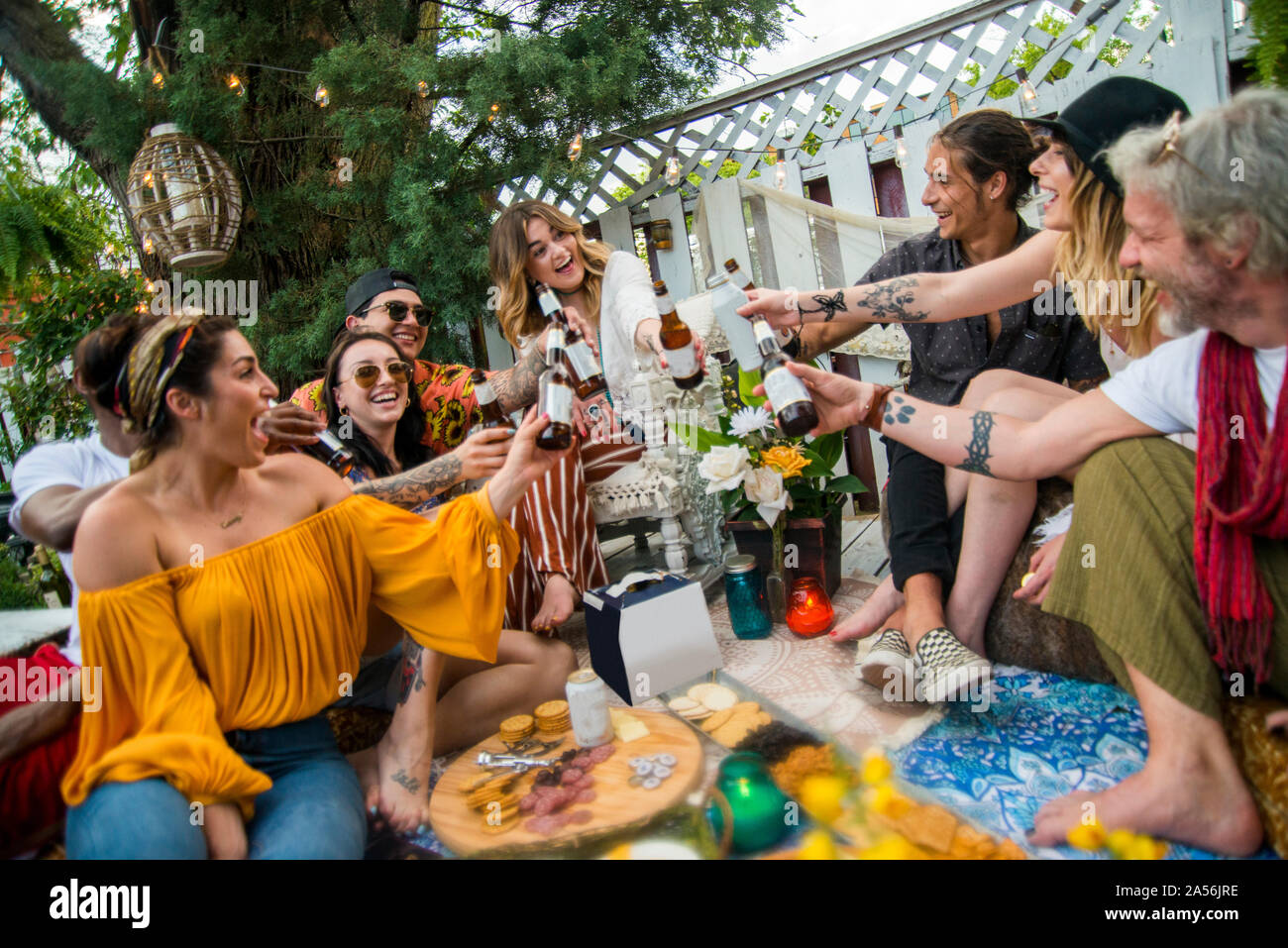 Männliche und weibliche Freunde machen ein Toast mit Flaschenbier auf Gemeinschaftsebene Garden Party Stockfoto