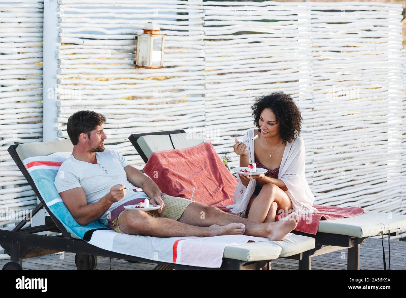 Paar sprechen und genießen Himbeere Kuchen auf Liegestühlen Stockfoto